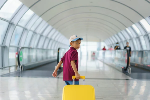 亚洲男孩身穿T恤和短裤在机场候机楼行走 准备在登机门登机 — 图库照片