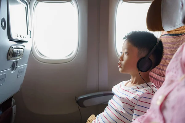 在漫长的飞机飞行过程中 亚洲小孩和他的母亲一起欣赏和观看卡通片 子女旅行假期概念 — 图库照片