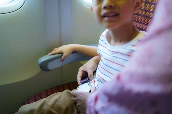 亚洲男孩在机舱系好安全带 与母亲共度安全假期 — 图库照片