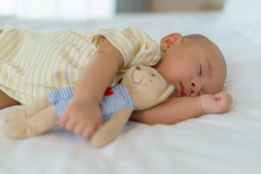 Yeni doğmuş bir çocuğun portresi uyuyor ve oyuncak ayısına sarılıyor. Evdeki yatak odasındaki yatakta.