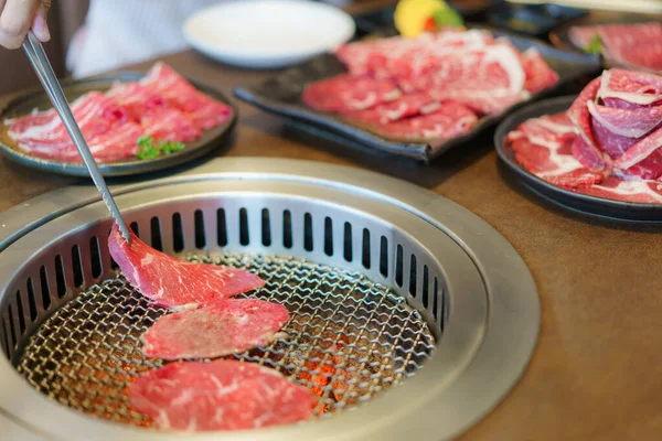 女性の手は 和牛を皿の上に置くために舌を使い 炭をグリルする準備ができて 日本のレストランでの食事体験を強化します — ストック写真