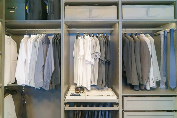 Explore the epitome of sophistication with a collection of meticulously hung men\'s suits and shirts in a well-organized closet. This scene exudes a refined sense of style, offering a glimpse into the world of tailored fashion.