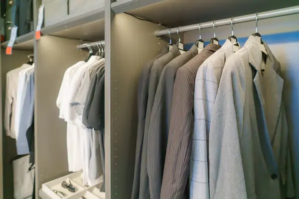 Explore the epitome of sophistication with a collection of meticulously hung men\'s suits and shirts in a well-organized closet. This scene exudes a refined sense of style, offering a glimpse into the world of tailored fashion.