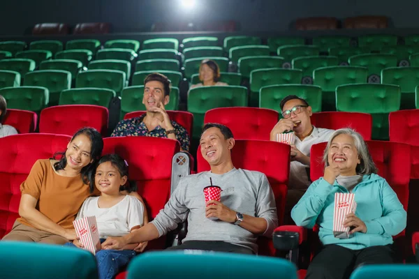 Asian parents and their child happily watch a movie, enjoying popcorn together in the cinema shared laughter, bonding, and the simple pleasures of a delightful cinematic experience