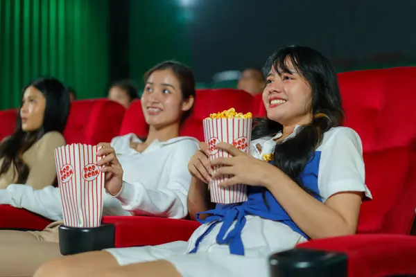 女性のグループは喜んで映画を見ます 各手でポップコーンの袋を保持しています ストックフォト