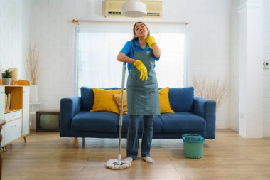 Hizmetçi, oturma odasının zeminini sürekli temizlerken temizlik ekibinin çalışkanlığını ve adanmışlığını yansıtıyor. Evin her köşesinde kusursuz bir mükemmelliğe ulaşma kararlılığını sergiliyor..