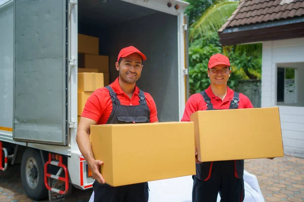 Two male delivery professionals as they hold parcels, ready to deliver them to customers at their doorstep