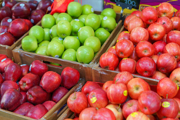 Wooden crates filled with a variety of fresh red and green apples on display at a local farmers market, showcasing organic and healthy produce