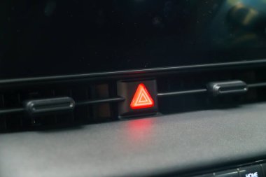 Modern otomotiv güvenliğinin kalbinde, yakın plan bir acil durum tehlike ışığı şalterinin kırmızı ışığını ortaya çıkarır. Bir dokunuşta hazır olan bu hayati bileşen, her türlü yol kenarı mücadelesine hızlı yanıt veren bir hazırlık feneri gibi duruyor.