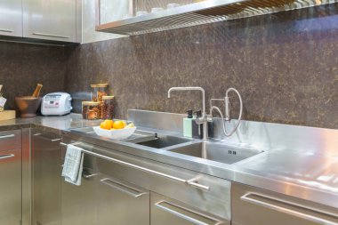 Modern bir mutfağın iç çekimleri. Parlak bir soba, şık bir lavabo ve sofistike bir egzoz kapağı olan bu alan, fonksiyonel tasarımın ve çağdaş zarafetin mükemmel bir birleşimini temsil ediyor.