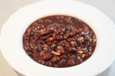 Beyaz tabakta pişmiş kırmızı fasulye.