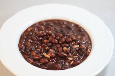 Beyaz tabakta pişmiş kırmızı fasulye.