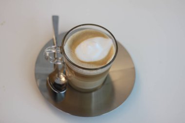 Latte coffee with white foam in a glass cup