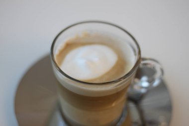 Latte coffee with white foam in a glass cup
