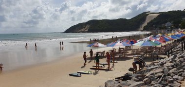 Punta Negra Beach, Natal, Rio Grande do Norte, Brezilya, Mart 05.2023: Monitörlerinin yanındaki kızlar Punta Negra Plajı 'ndaki Morro de Careca' nın yanındaki sörf dersinden önce esneme hareketleri yapıyorlar.