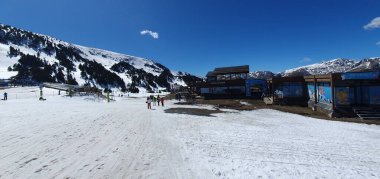 Soldeu, Andorra, Nisan, 04, 2023: Kayak sezonunun sonunda, güneşli bir günde çok az kar bulunan Grandvalira tatil beldesinde kayak manzarası