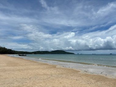 Beyaz kumlu ve mavi gökyüzü olan bir sahil.