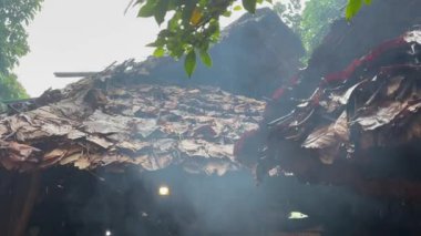 Yağmurlu bir günde Karen kabilesinin tipik yaprak çatısı Doi Inthanon Ulusal Parkı 'ndan yükselen duman Tayland, Hindiçin, Asya' daki Chiang Mai 'nin kuzeyinden yükseliyor.