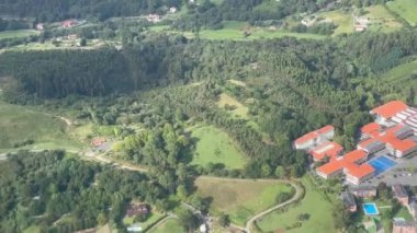 Yeşil çimenleri ve ağaçları olan küçük bir köyün havadan görünüşü.