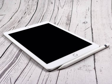Beyaz ahşap arka planda tabletin bir kopyası. Beyaz ahşap masada elektronik tablet. Tablet bilgisayar modeli. Elektronik cihaz. Teknoloji konsepti.