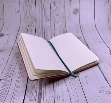 Beyaz ahşap arka planda Not Defteri 'nin bir kopyası. Kalem, tükenmez kalem ve kağıt defter beyaz ahşap masada. Dilek listesi için not defteri. Boş sayfalar. Sayfa Mockup. Planlama.