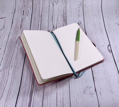 Beyaz ahşap arka planda Not Defteri 'nin bir kopyası. Kalem, tükenmez kalem ve kağıt defter beyaz ahşap masada. Dilek listesi için not defteri. Boş sayfalar. Sayfa Mockup. Planlama.