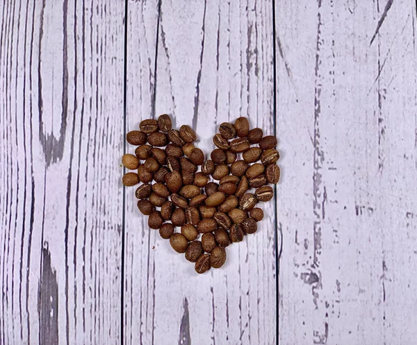 Coffee beans in heart shape isolated on wooden background. Espresso ingredients. Raw coffee beans. Espresso lover. Coffee heart.