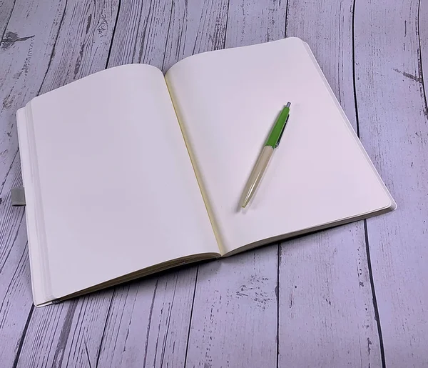 关于白色木制背景的笔记本的模型 白色木制桌子上的钢笔 圆珠笔和纸笔记本 希望列表的记事本模型 空白页 页Mockup 免版税图库照片