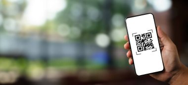 Cep telefonu uygulaması ile QR kodları taranıyor ve perakende süpermarket arka planında mal ve hizmetler için ödeme yapılıyor