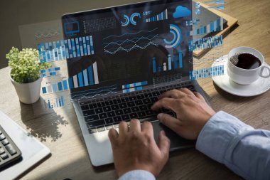 Analist masaüstünde bir bilgisayar ve panel Veri Yönetim Sistemi proje analizi kaynağı finansal grafik iş performansı kullanır