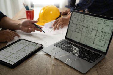 Mühendis A inşaat teknolojisi işçisi inşaat alanında bilgisayar kullanan bir mühendisi kontrol ediyor. Mimarlık, geliştirme ve inşa planında mühendis ekipleri