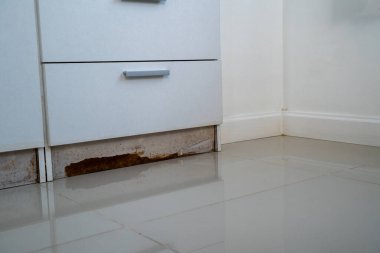 Dolapta beyaz bir dolap ve yerde kahverengi bir leke var. Sel sonrası dolapta iki çekmece var.