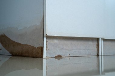 Dolapta beyaz bir dolap ve yerde kahverengi bir leke var. Sel sonrası dolapta iki çekmece var.