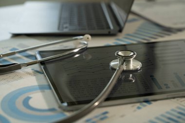 Doktor hasta bakımını iyileştirmek için modern teknoloji ve tıbbi analiz kullanıyor. Doktor, steteskop ve grafiklerle araştırma yapıyor.