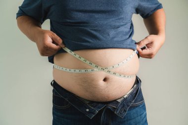 Kilolu bir adam karnını tutuyor, sağlıksız yaşam tarzından memnun değil, kilo vermek ve daha iyi spor yapmak istiyor. Şişman, şişman adam.