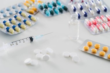 İlaç. Bir şişe ilaç ve şırınga. Masada bir sürü farklı renkli hap var.