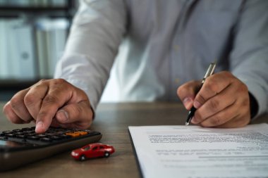 Hesap makinesi, kalem ve belgelerle çalışan, muhtemelen mali ya da hukuki evrakları inceleyen, evrak sigortası yapan kişinin sigortası