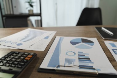 Rapor dosyası resmi, finansal dökümanlar, grafikler, hesap makinesi ve not defteri olan, odaklı veri ile çalışma veya analiz ortamını gösteren bir masayı gösterir.