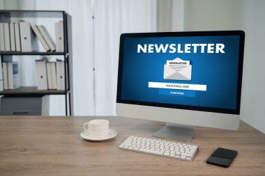 Modern ofis çalışma alanındaki masaüstü bilgisayarında, kahve fincanı ve akıllı telefonlu haber aboneliği kavramı, e-posta pazarlaması, iş iletişimi ve dijital tanıtımı temsil etmektedir..