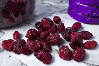 Kurutulmuş yaban mersini. Kümeler halinde doğan meyveler ilk başta beyazdır ve olgunlaştıkça tamamen olgunlaştıklarında maviye dönüşmek için kırmızımsı mora dönerler..