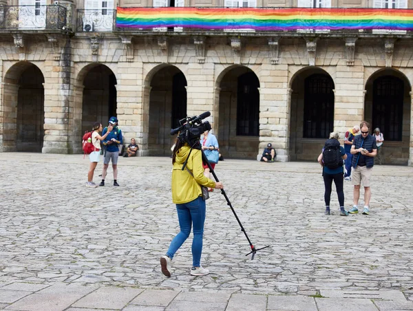 Santiago de Compostela, 30 Haziran 2023. Kamera operatörü. Elinde kamera ve tripodu olan bir kadın Plaza del Obradoiro 'da yürüyor.