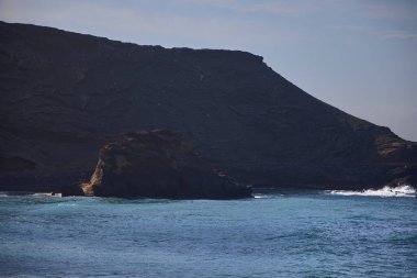 Sea and rocks. Cliffs in El Golfo, a coastal village on the island of Lanzarote (Spain). clipart