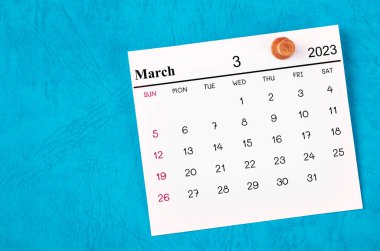 Mart 2023 ve ahşap raptiye mavi arkaplanda.