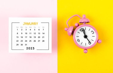 2023 yılı Ocak ayının takvimi. Arka planda pembe alarm saati var..