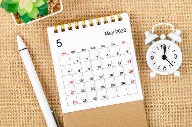 May 2023 Monthly desk calendar for the organizer to plan 2023 year with alarm clock and pen on sack background. clipart
