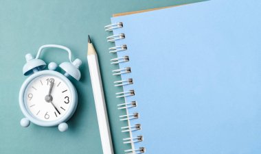 Boş günlük ve mavi arkaplanda kurşun kalemli alarmlı saat.