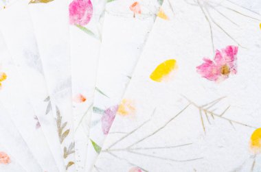 Kuru yapraklı ve çiçekli farklı el yapımı kağıt yığını.