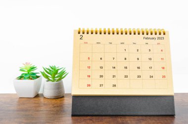 February 2023 Monthly desk calendar for 2023 year with small plant on wooden table. clipart