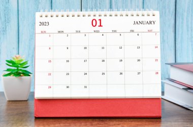 January 2023 Monthly desk calendar for 2023 year with the books on blue wooden background. clipart