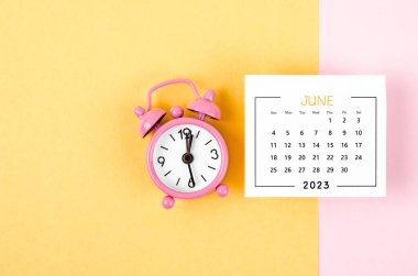 2023 Haziran 'ının takvimi. Güzel bir arka planda pembe alarm saati var..